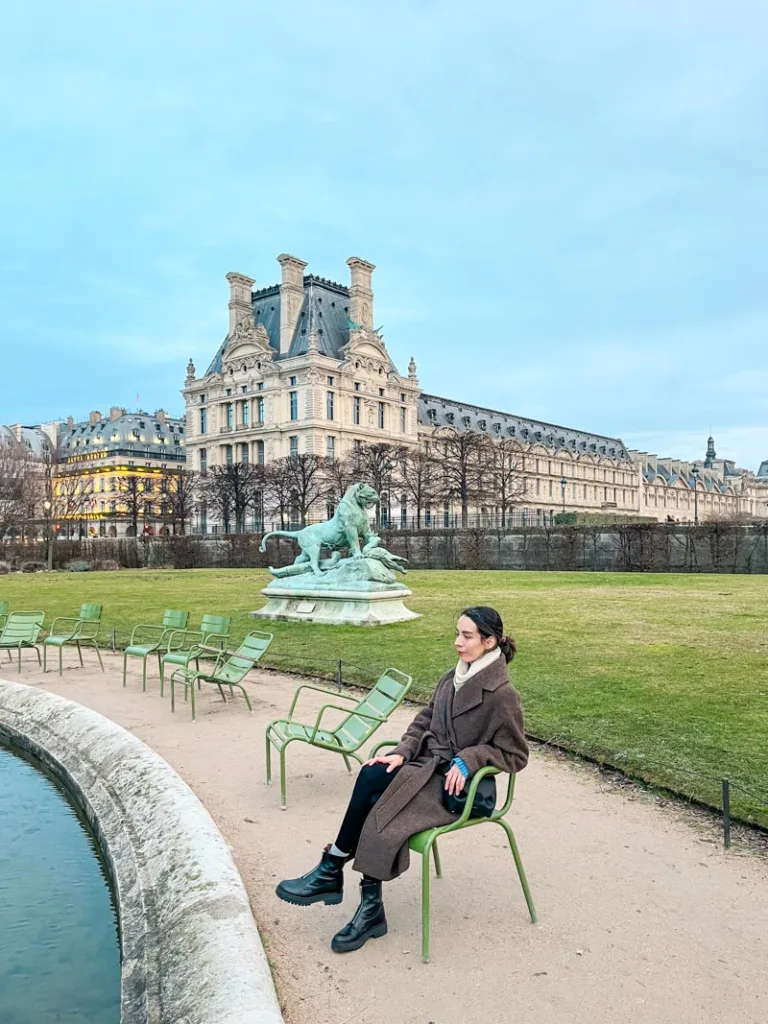 woman sitting on a green chair by the pond at jardin des tuileries in paris