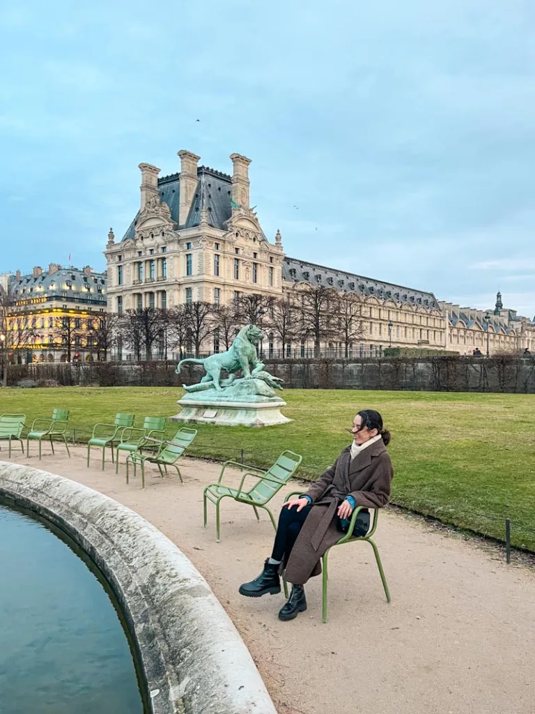 woman sitting on a green chair by the pond in jardin des tuileries