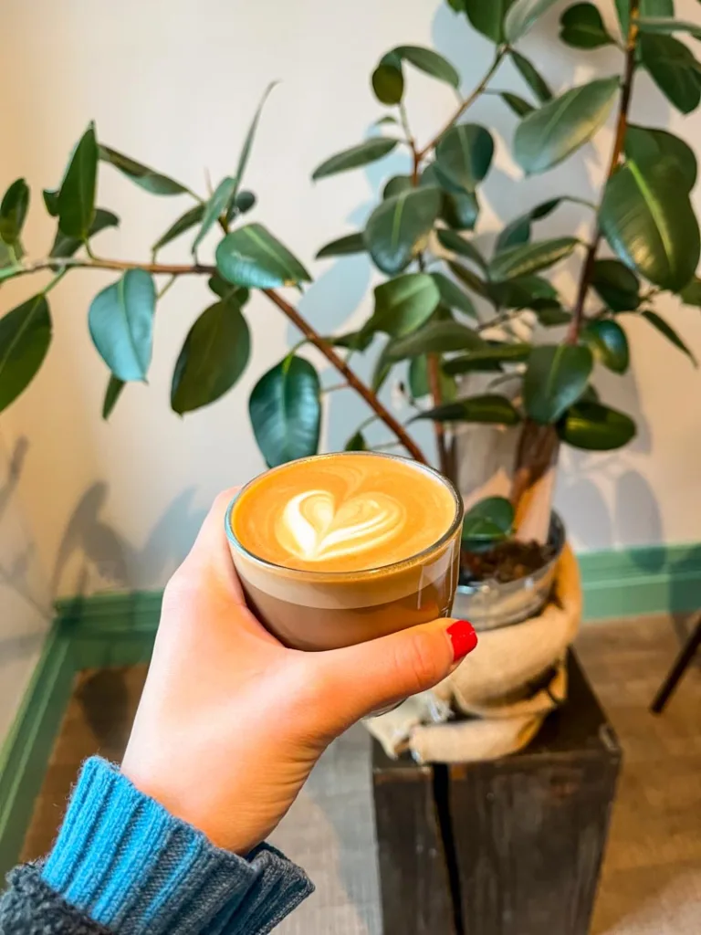 hand holding a flat white at amoret coffee in notting hill, london