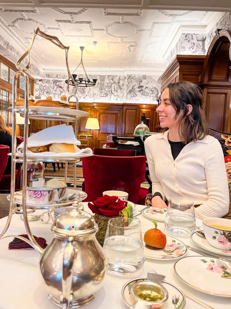 woman having afternoon tea at browns hotel london, the table is set with te cups and a pastries tower