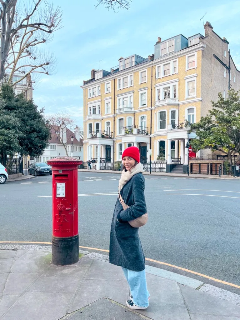 woman standing next to a red mail box in kensington london