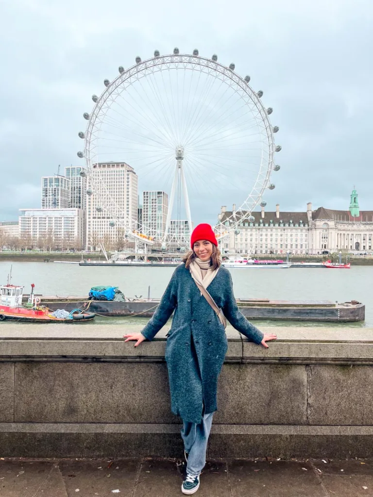 woman smiling in front of the london eye across the river thames