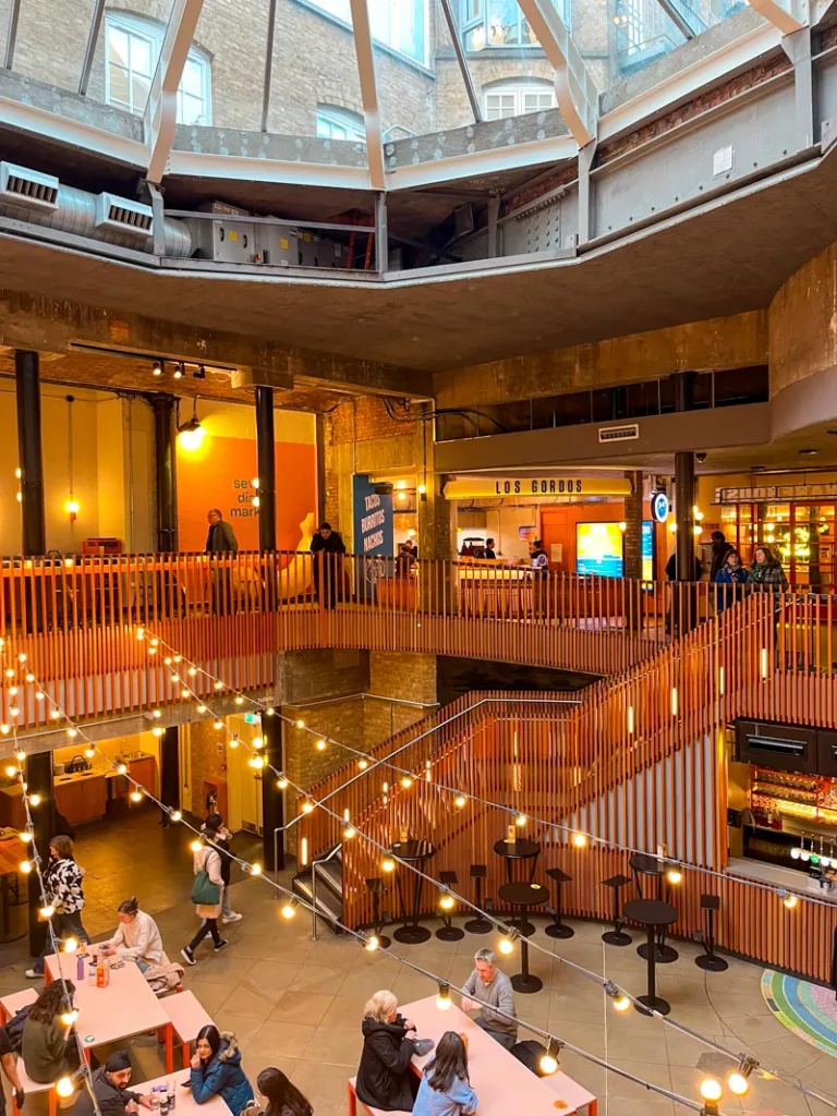 vibey seven dials food court in london with wooden decor and fairy lights handing