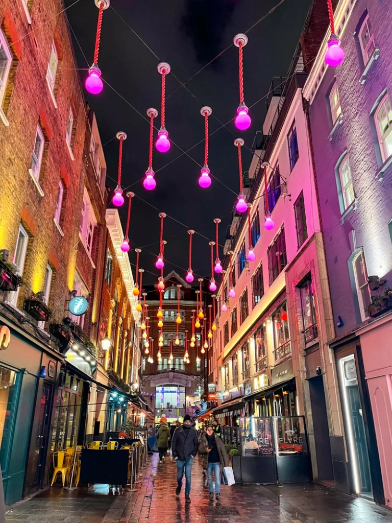 colorful lights hanging above a street in soho, london at night