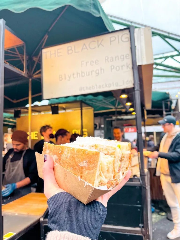 hand holding a pulled pork sandwich from the black pig food stand at borough market