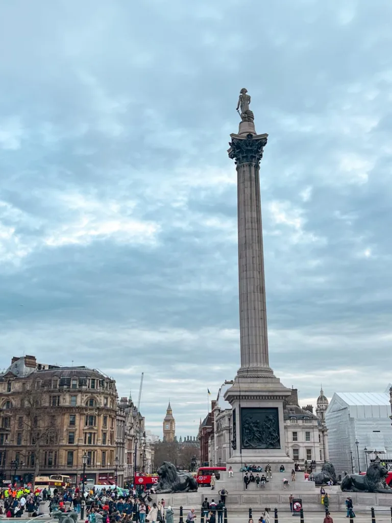 view of nelson's column in trafalgar square in london, with a view of big ben at the back