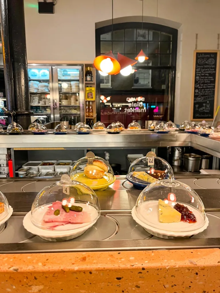 small cheese plates on a conveyor belt at a restaurant in seven dials market in london