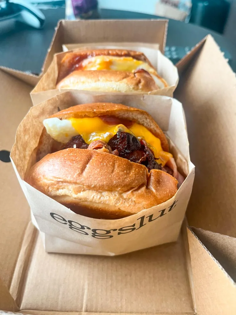 two hearty egg breakfast sandwiches wrapped in egg slut branded paper in london
