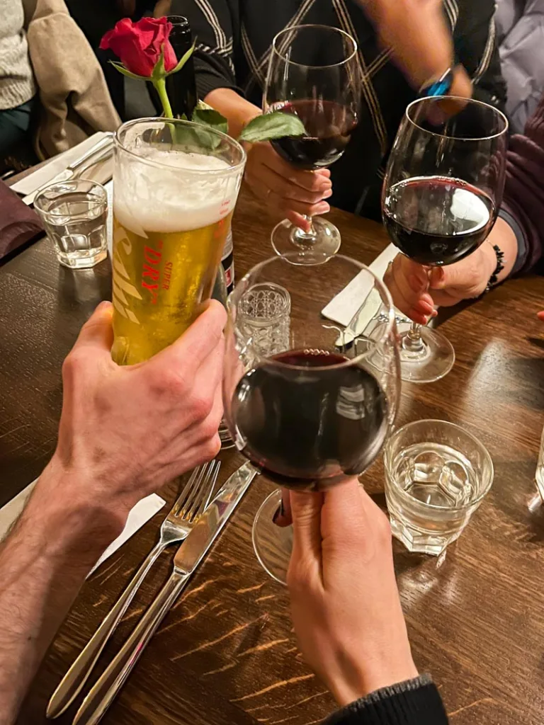 three glasses of red wine and a beer cheering in the middle of a table in the lamb and flag pub in london