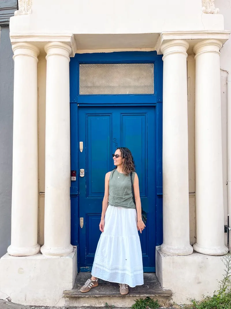 woman standing in front of the famous notting hill blue door in london