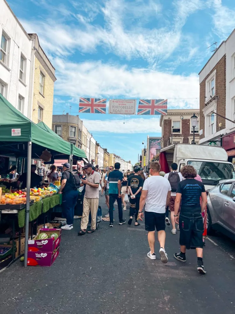 fruit stand and other vendors lining the street at the portobello road market in london