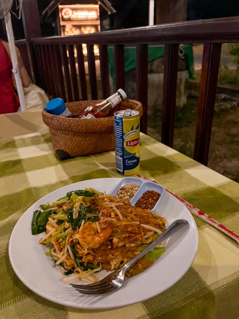 pad thai on a green checkered table cloth at pranees kitchen in koh tao, thailand