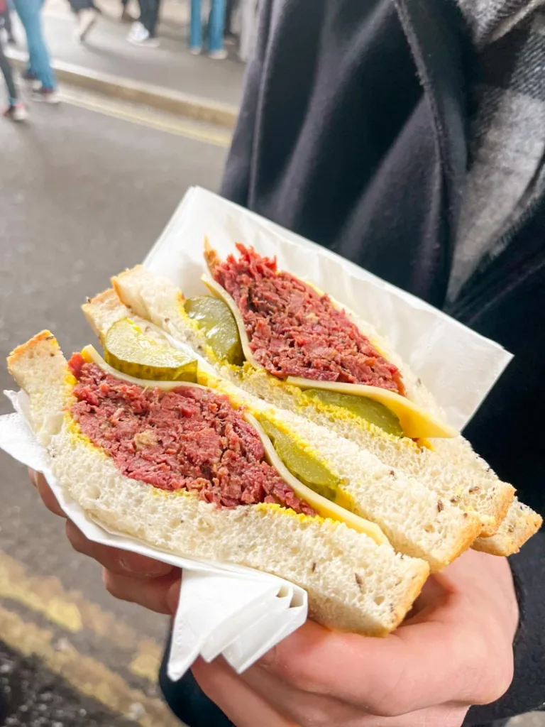 hand holding a roast beef sandwich from. a stand at borough market in london