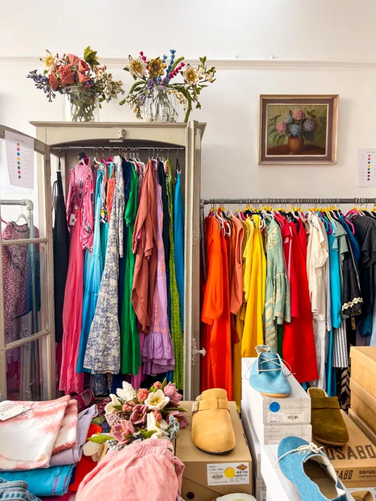 racks of neatly organized clothes by color at royal trinity hospice portobello charity shop in notting hill, london