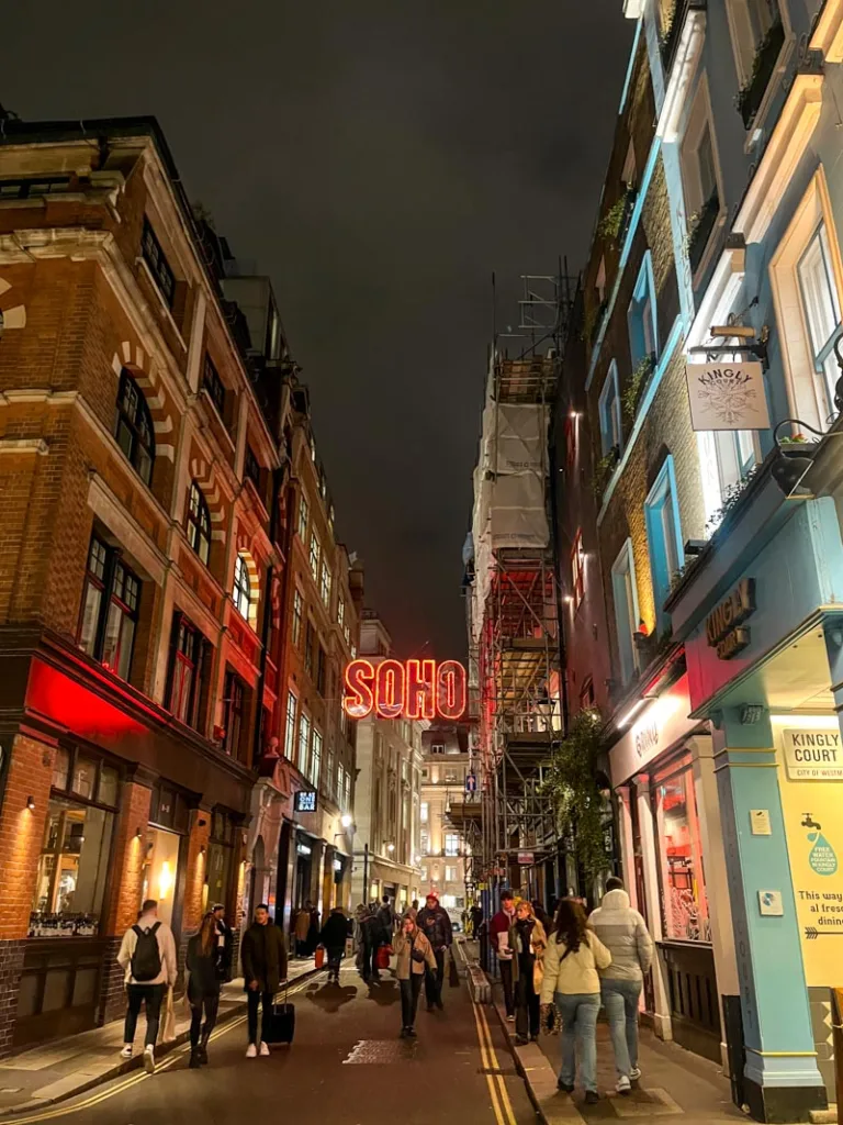 red soho neon light sign above a street in soho, london