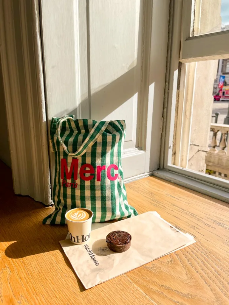 A cortado and a small chocolate pastry on a wooden bar at watch house coffee shop in london