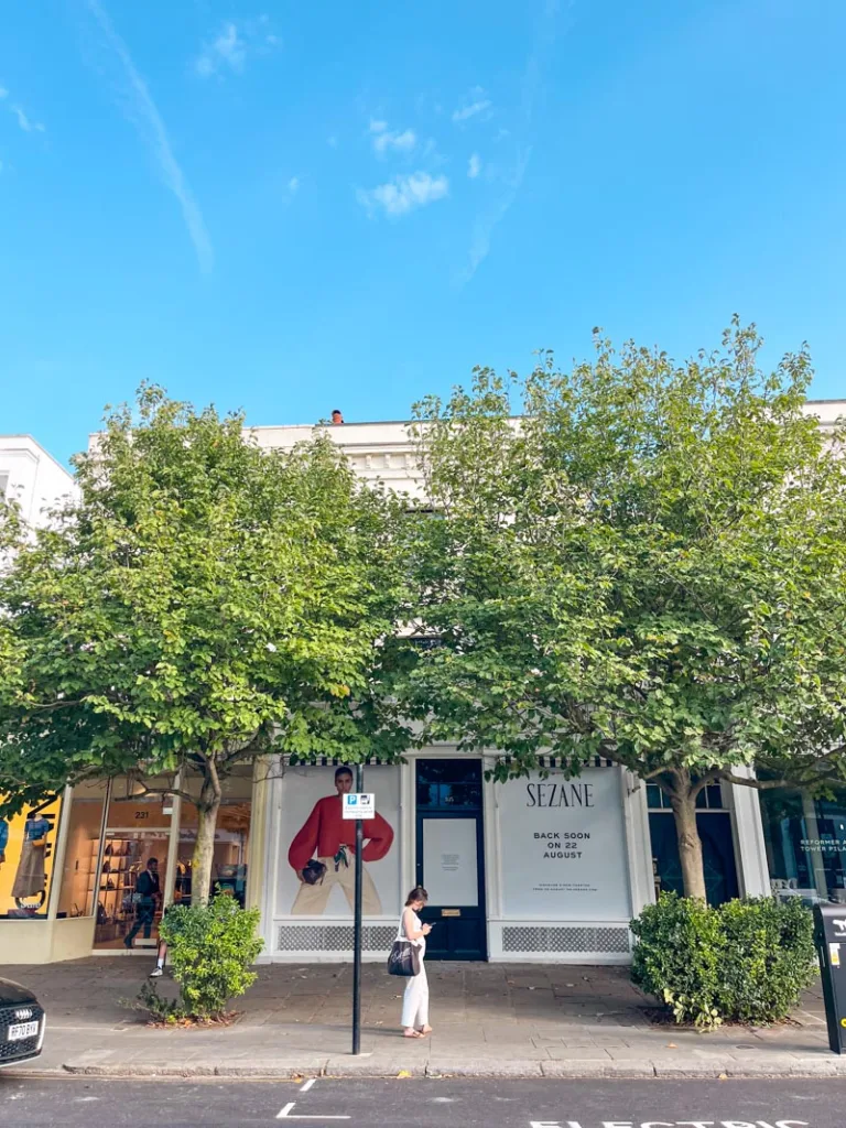 woman standing in front of a sezane shop in westbourne grove in notting hill, london