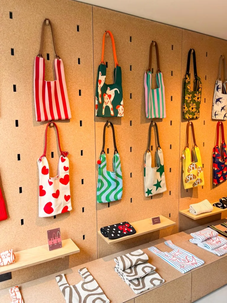 colorful printed totes displayed on a cork wall at yessing shop in notting hill, london