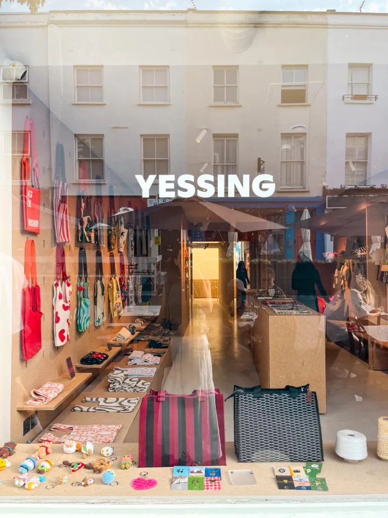 view of totes and accesories through the front shop window of yessing shop in notting hill, london